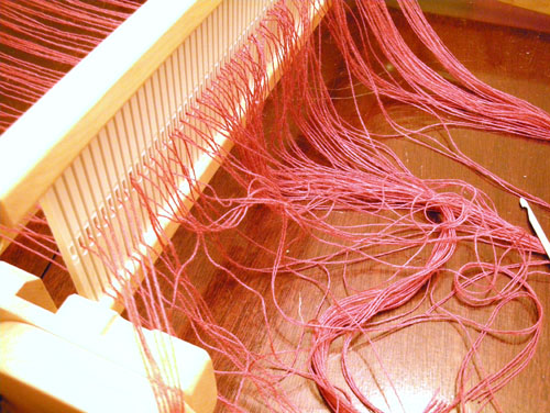 Pulling the warp threads through the slots